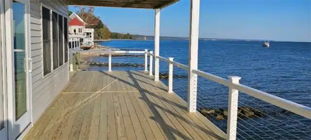 Photo of wooden deck along the water with cable railing