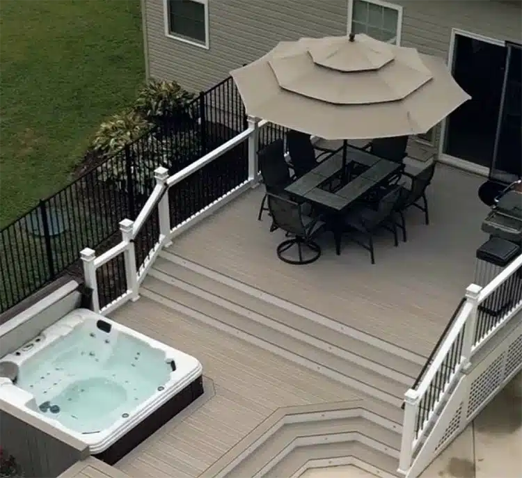 Aerial view of multi-level deck with hot tub, umbrella, and outdoor furniture. Custom deck builder maryland