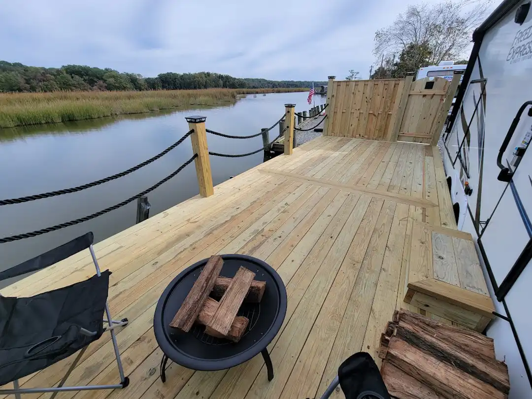 Photo of wooden deck along waterfront with rope railings