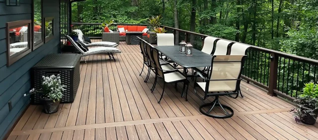 photo of an elevated composite deck with outdoor furniture in a wooded setting, demonstrating just one of several custom deck ideas.