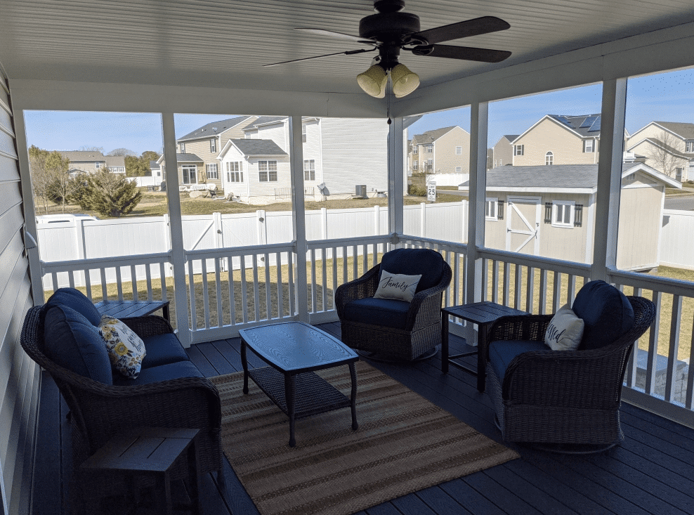 Photo of a cozy, screened-in porch with ceiling fan and wicker furniture - porch design ideas