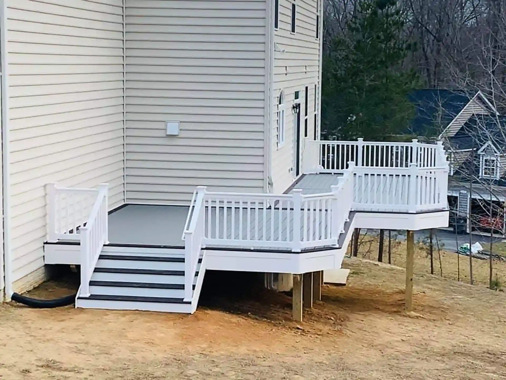 Two-level composite deck with white railing, built on a sloped yard with step-down transition