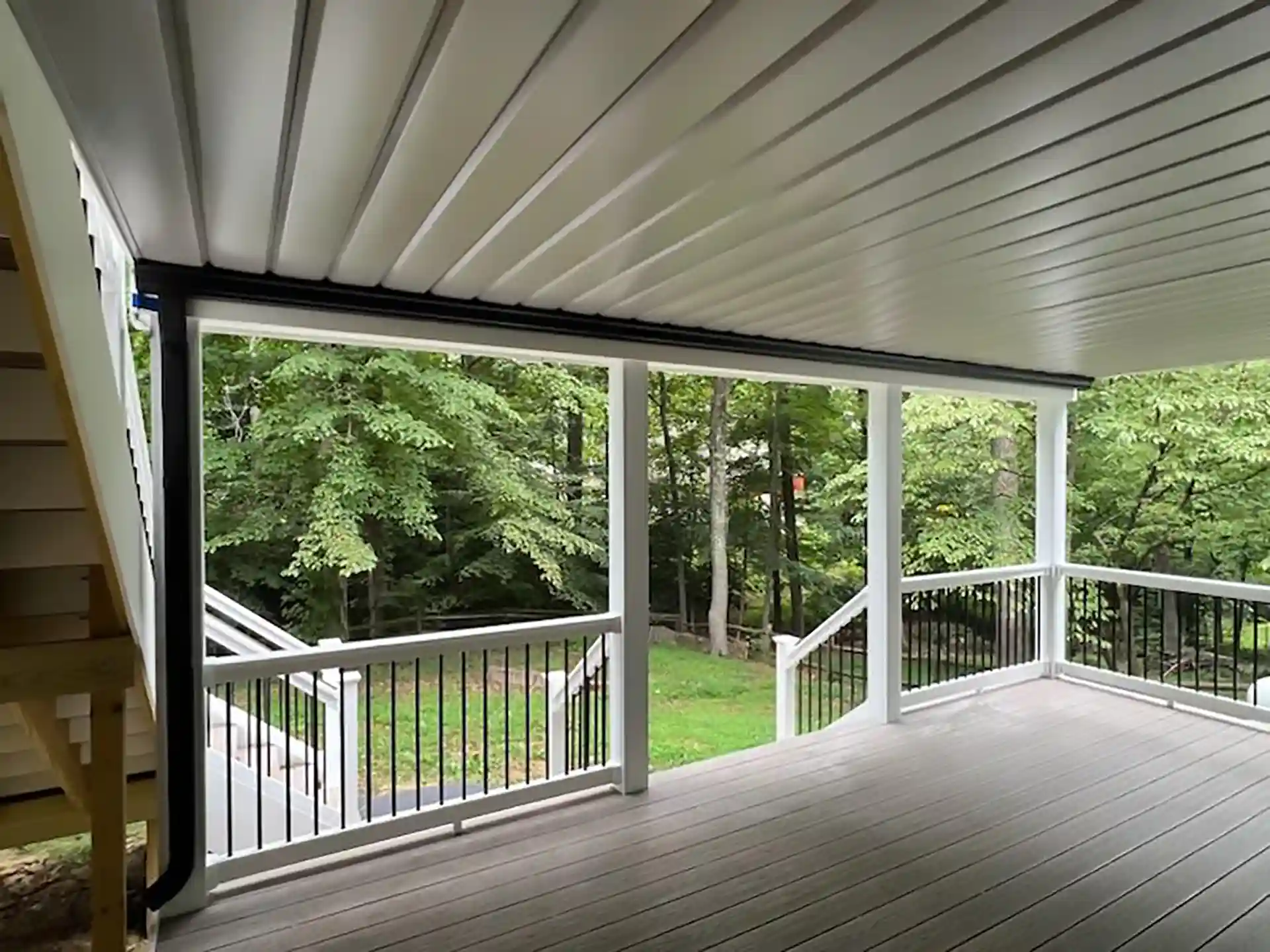 View from the covered upper-level deck overlooking the lower deck tier and wooded backyard