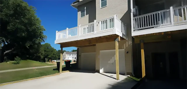 Under-deck area with a white railing and posts supporting a balcony above.